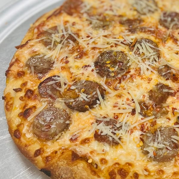 Close-up of a Bonilla's Pizza sausage pizza, topped with shredded cheese and red pepper flakes.